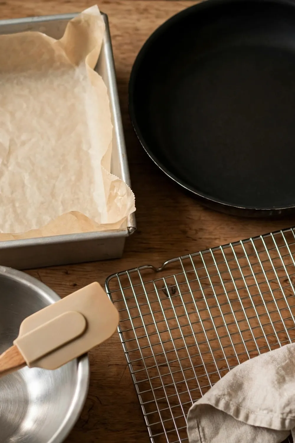 Light metal square pan lined with parchment beside a dark pan