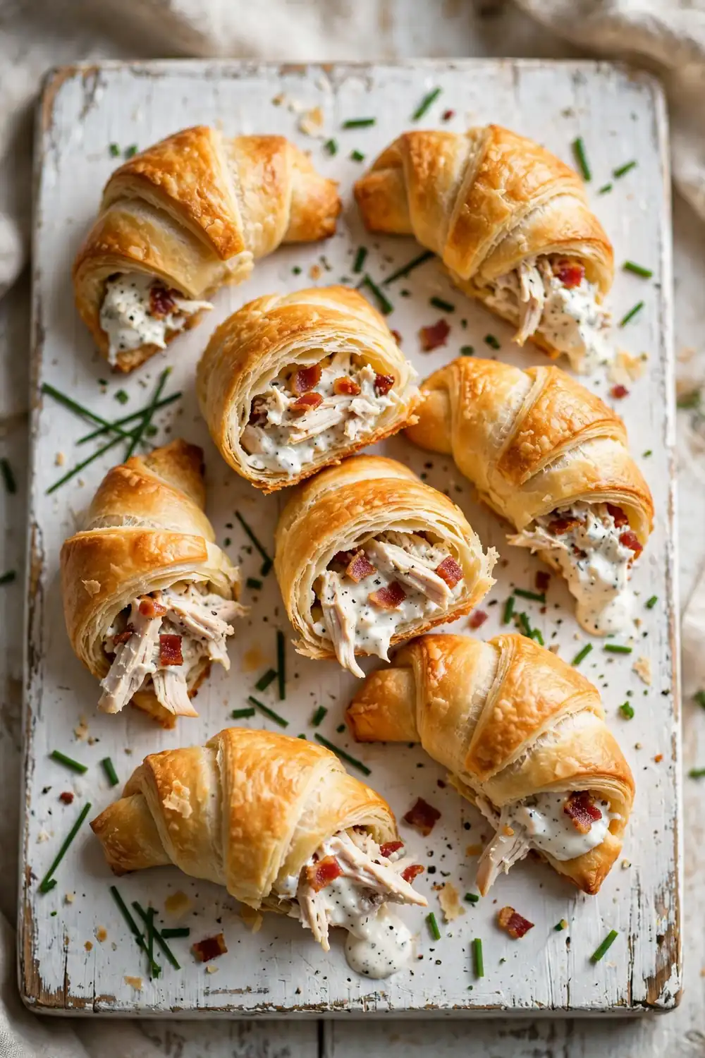 Golden crescent roll-ups filled with chicken, bacon and ranch cream cheese on a wooden board