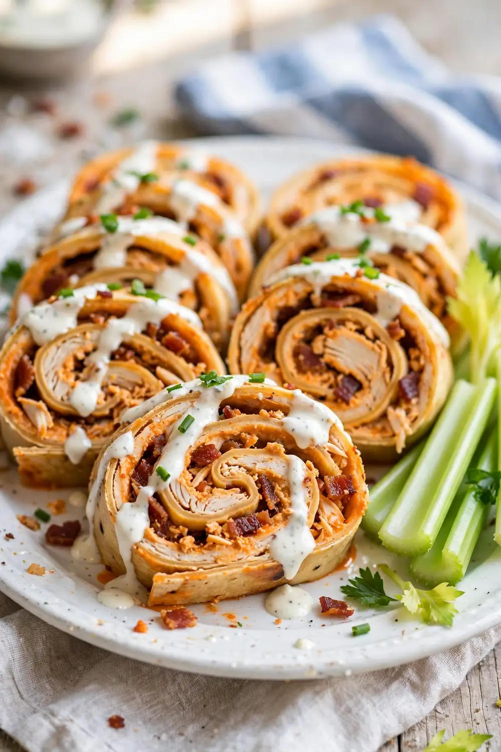 Buffalo chicken spiral rolls drizzled with ranch sauce on a platter