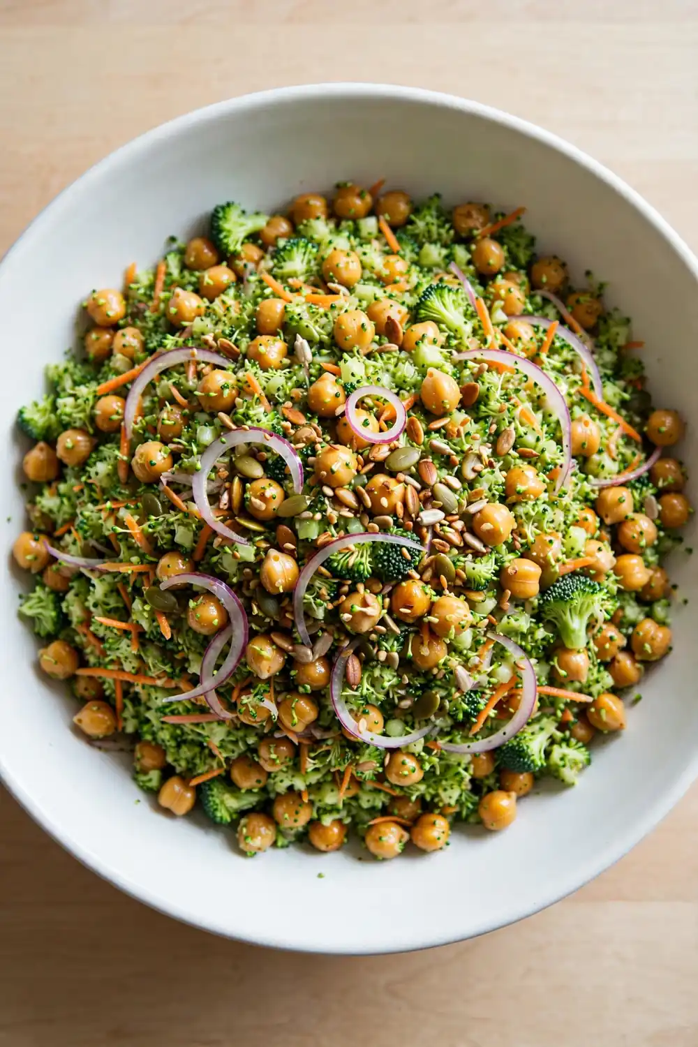 Classic chopped broccoli and chickpea salad in a bowl with shredded carrot and seeds