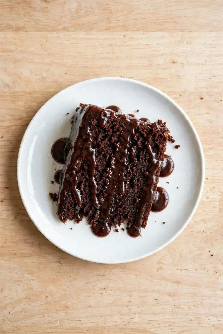 Classic cola cake slice with glossy cola glaze dripping down the sides on a white plate
