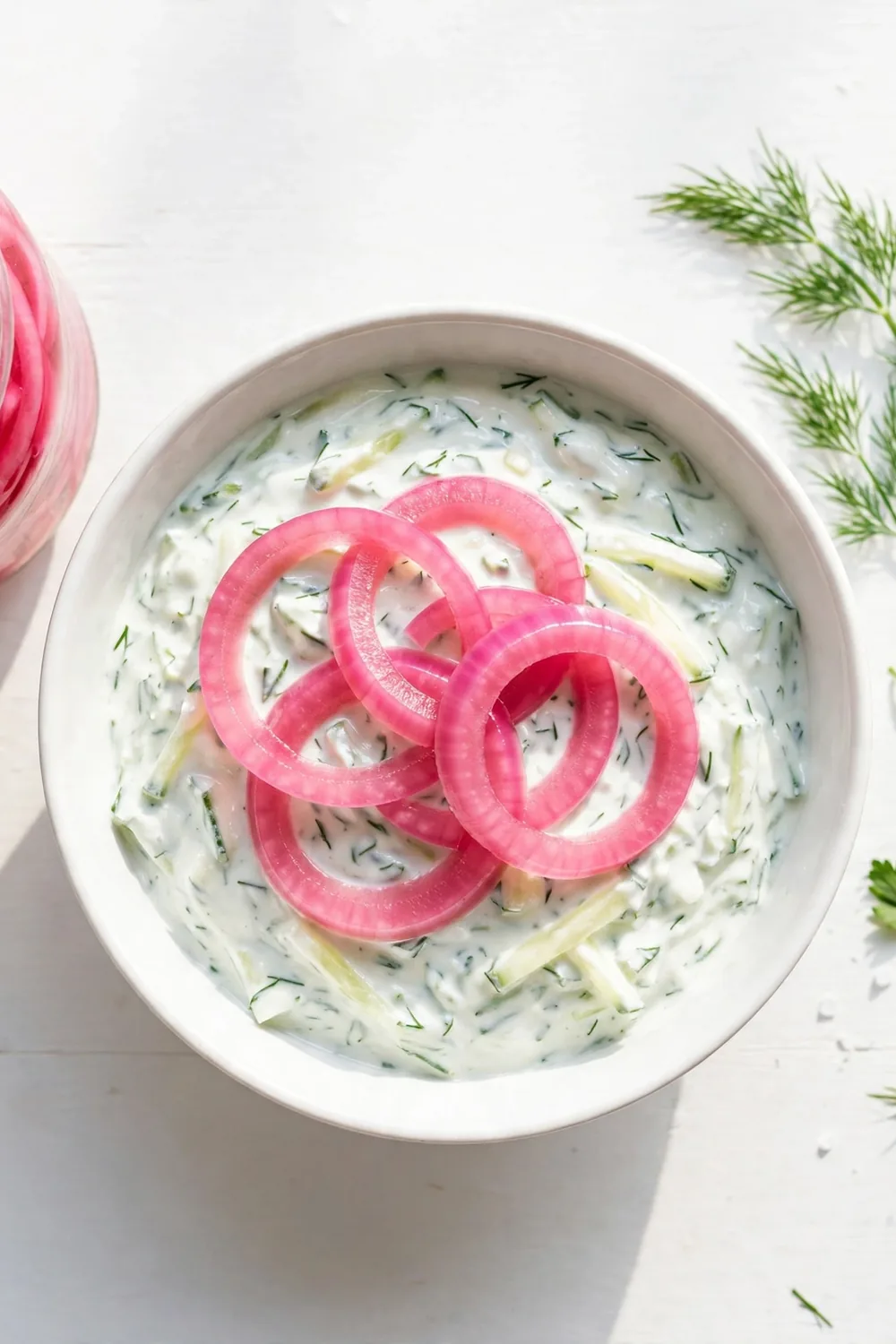 Tzatziki dip topped with pickled red onion slices and herbs