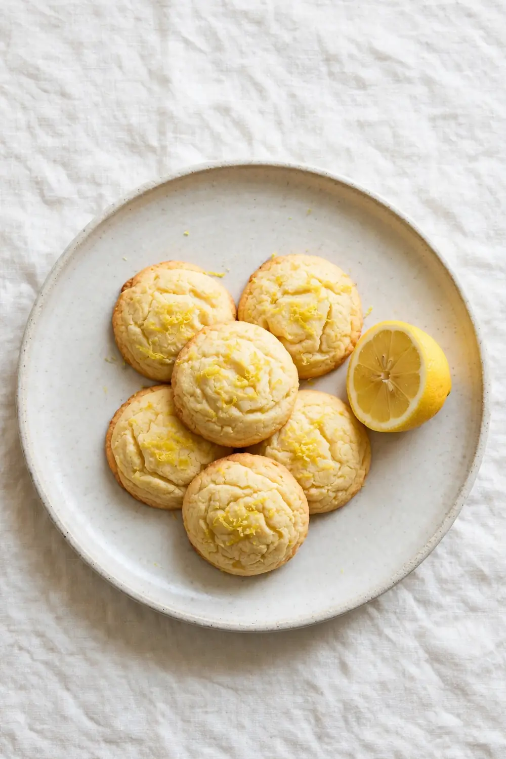 Lemon ricotta cookie rounds with olive oil and lemon on a ceramic plate