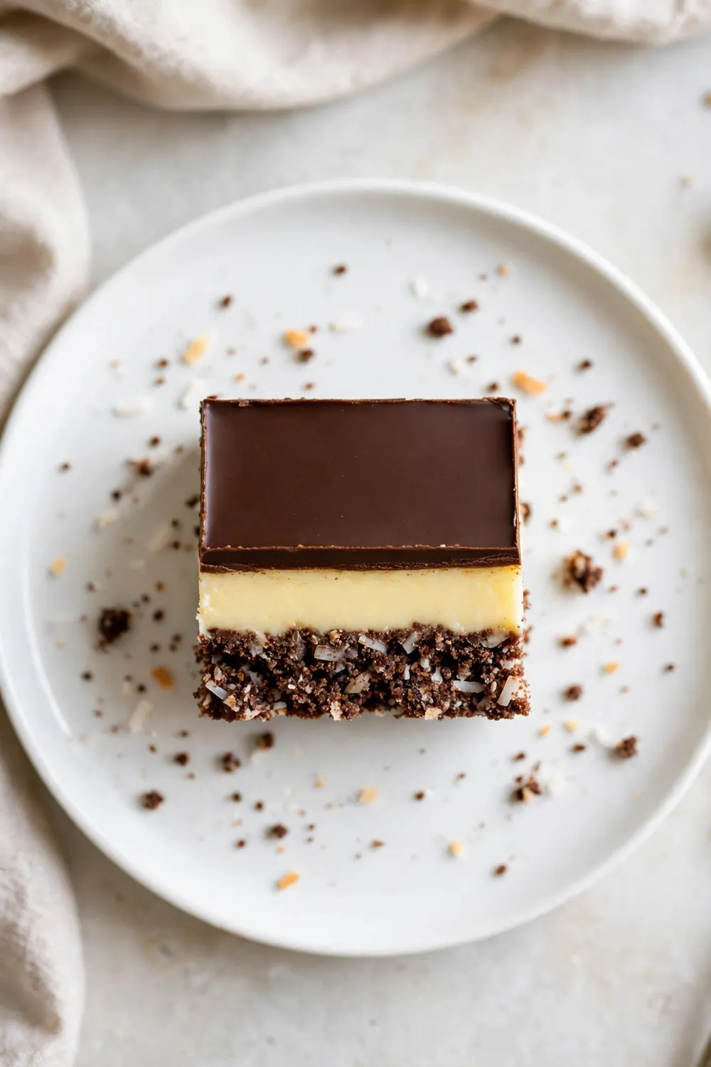 Classic Nanaimo bar square with three layers on a white plate