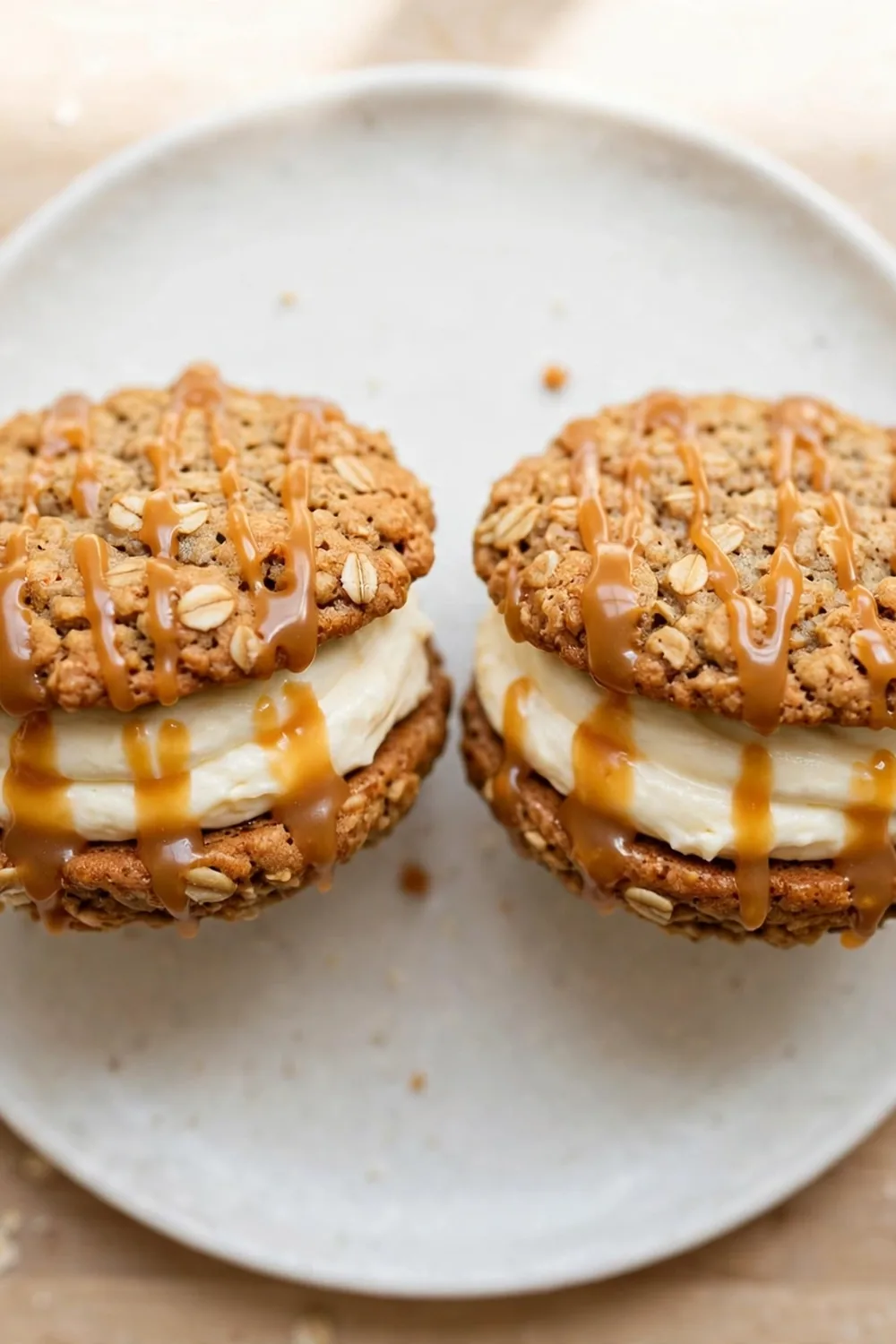 Classic chewy oatmeal cookie sandwich pie with vanilla cream filling and caramel drizzle on a white plate