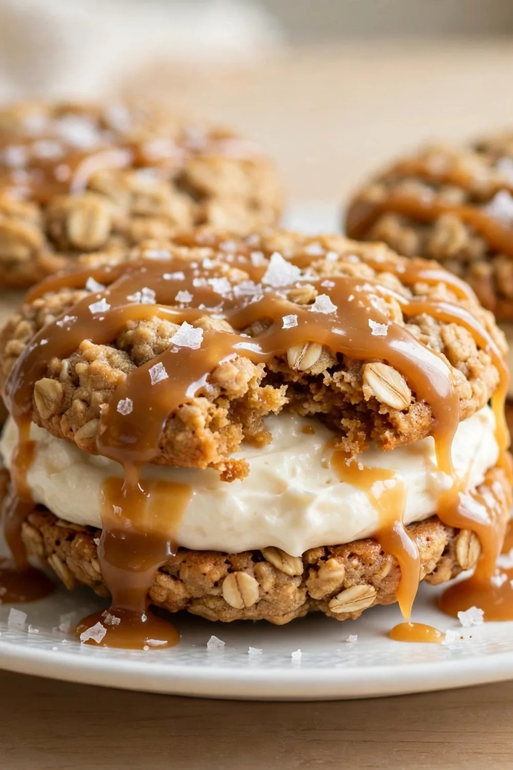 Oatmeal cookie sandwich pie with salted caramel drizzle and flaky sea salt on a white plate