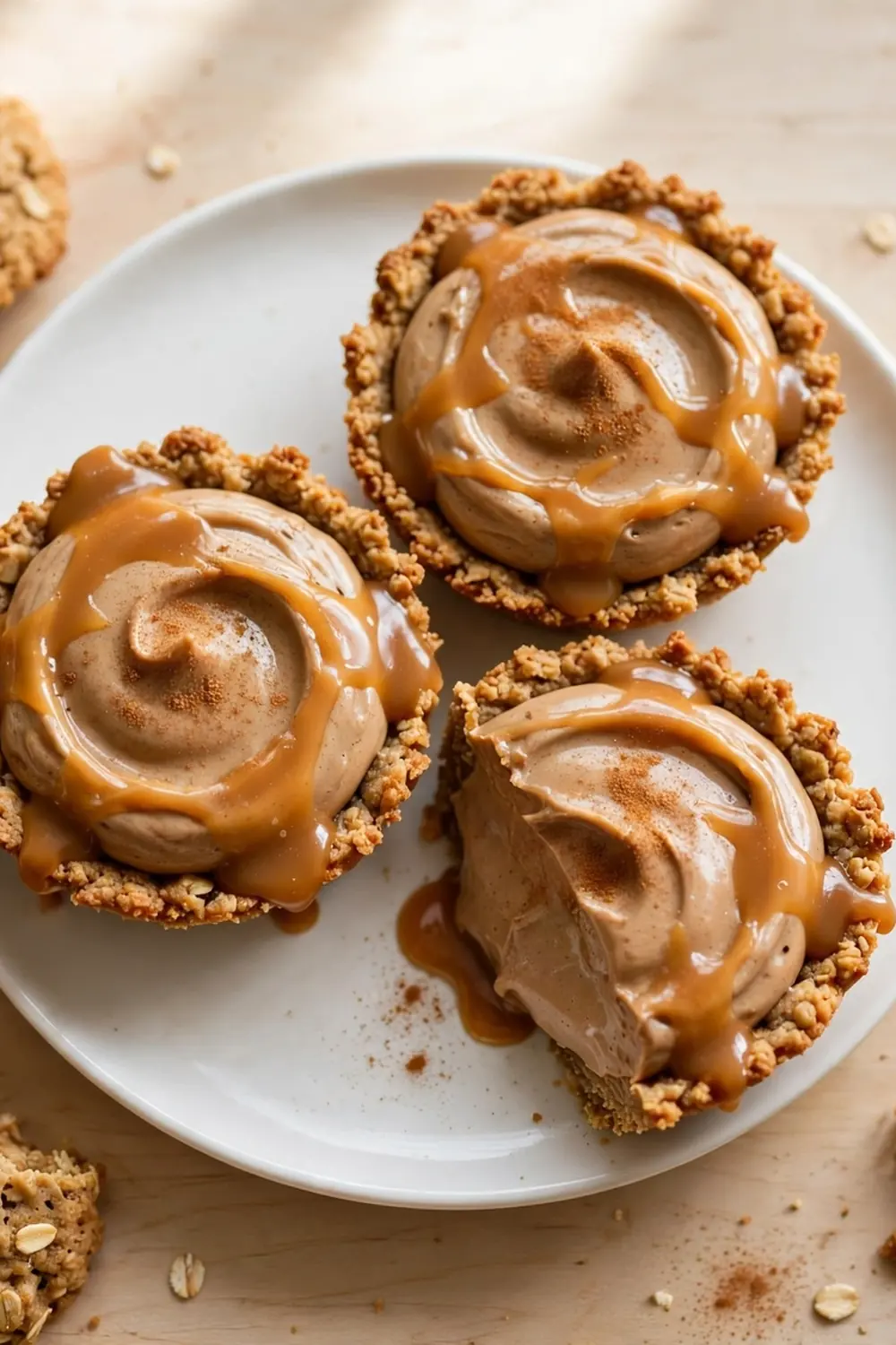 Oatmeal cookie sandwich pie with brown sugar cream filling, caramel drizzle, and cinnamon on a white plate