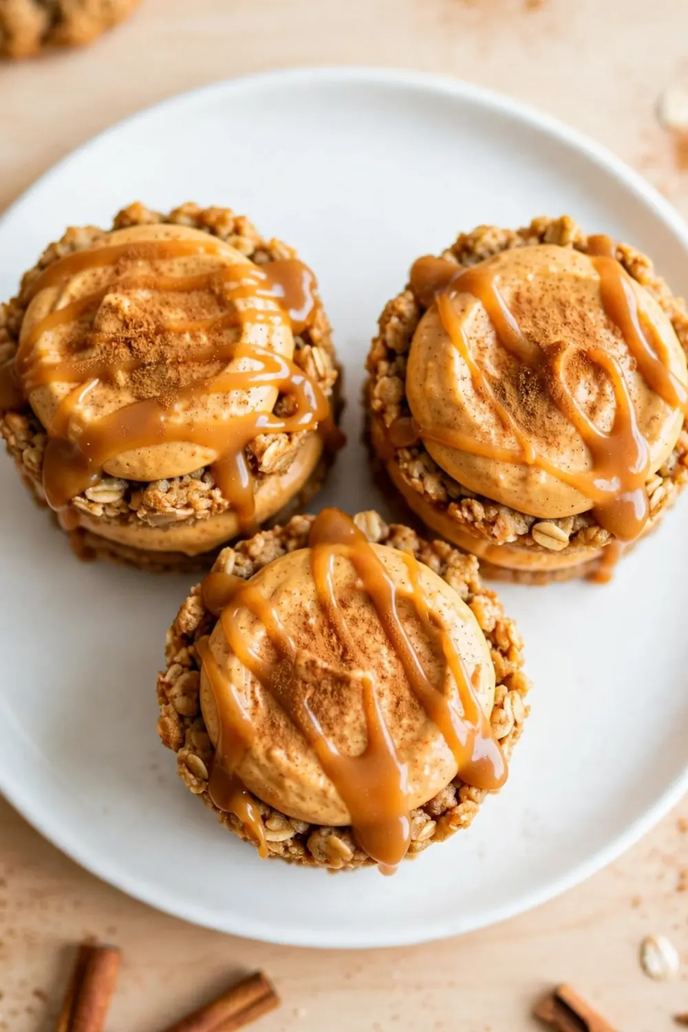 Oatmeal cookie sandwich pie with pumpkin spice cream filling and cinnamon dusting on a white plate