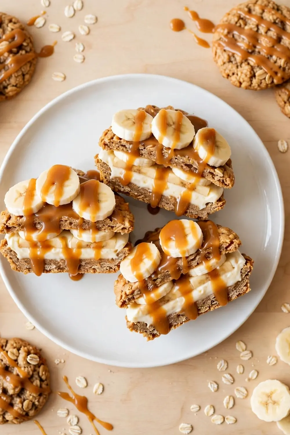 Oatmeal cookie sandwich pie with banana caramel stack, banana slices, and cream on a white plate