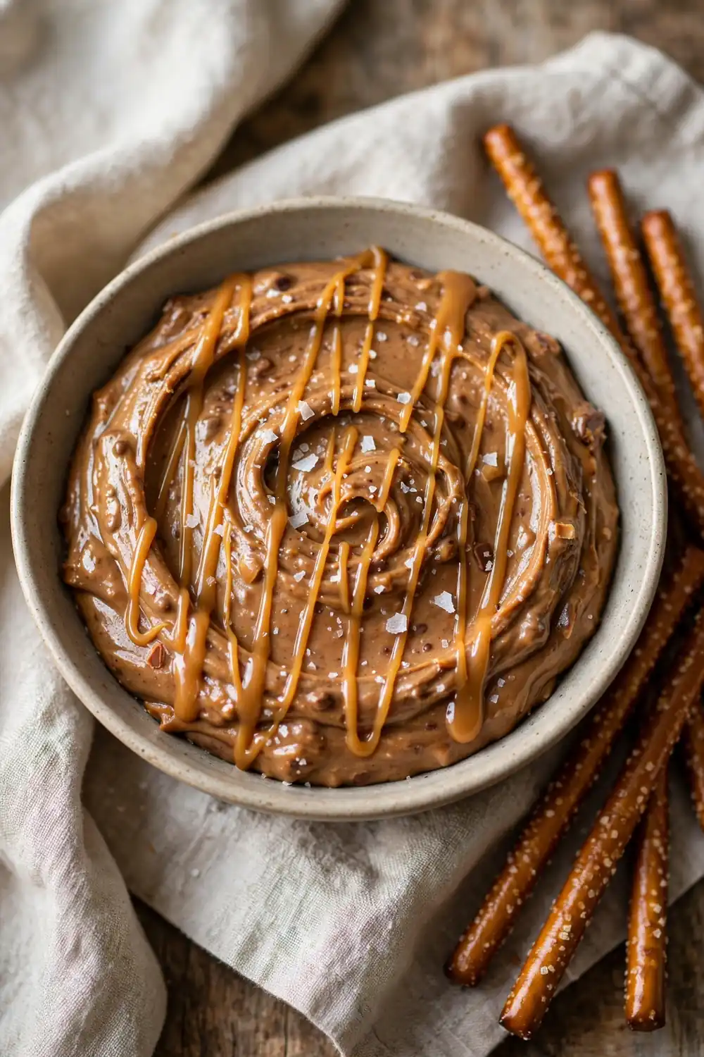 Peanut butter brownie batter in a bowl with salted caramel drizzle and flaky sea salt