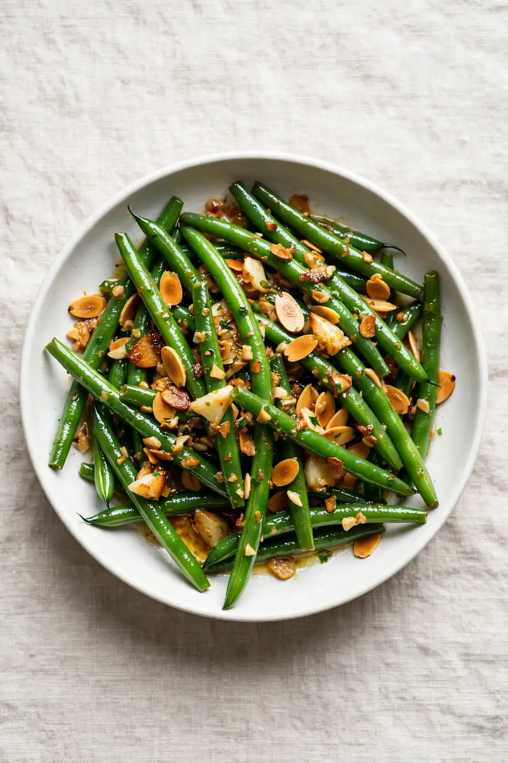 Green beans tossed with garlic butter and toasted almonds in a bowl